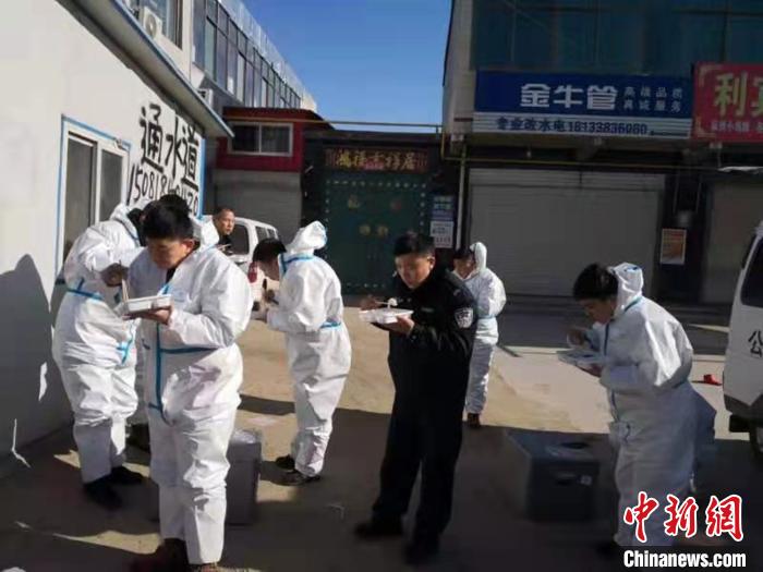 圖為藁城區(qū)增村鎮(zhèn)小果莊村疫情防控檢查站警員為暖和在陽光下吃飯?！堅露Y 攝