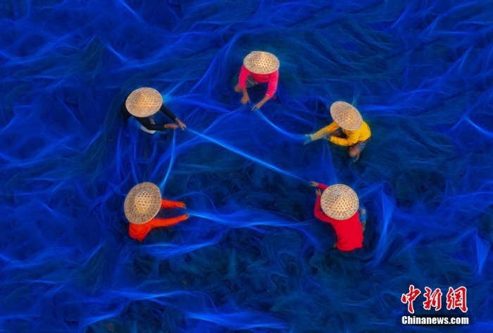 印度漁民修補藍(lán)色漁網(wǎng) 似置身深邃海洋