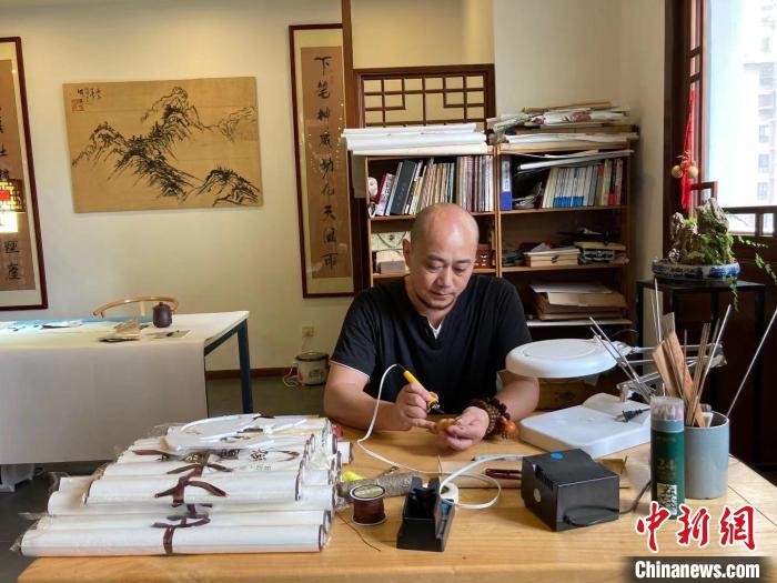 陶思俊正在進(jìn)行葫蘆烙畫創(chuàng)作?！￡愳o 攝