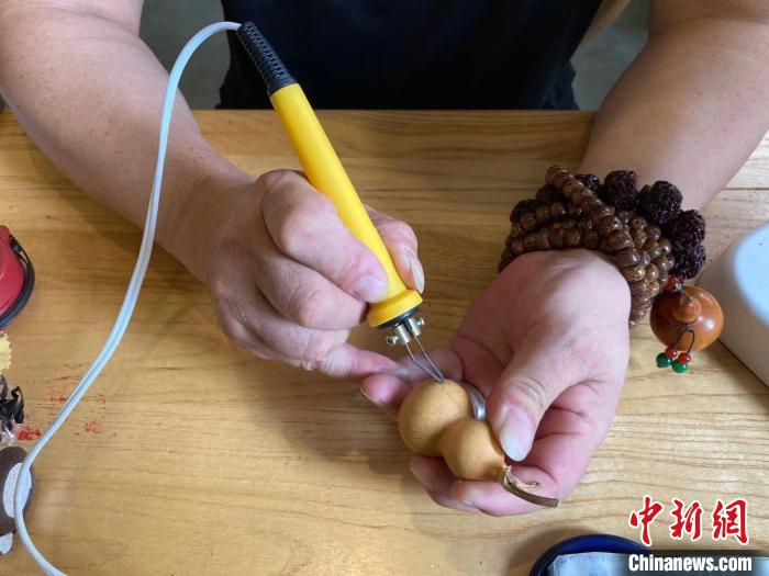 陶思俊正在進(jìn)行葫蘆烙畫創(chuàng)作?！￡愳o 攝