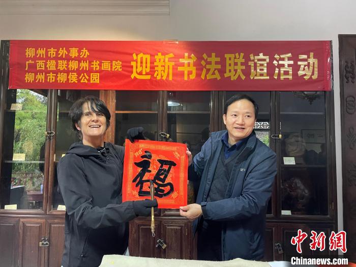 圖為一名英國人(左)展示其書寫的春聯(lián)?！×周?攝
