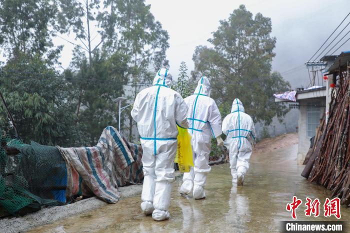 圖為在德?？h隆桑鎮(zhèn)果甫村，身著厚重防護服的歐秋潔和同伴步履蹣跚地行走。