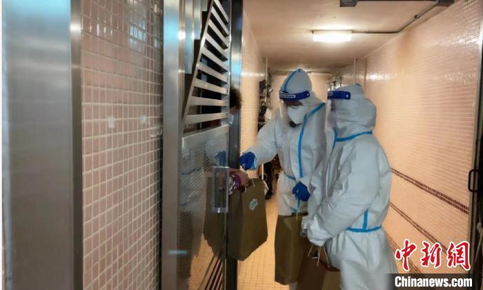 圖為吳學(xué)明和義工送抗疫物資到確診家庭手中?！∈茉L者供圖
