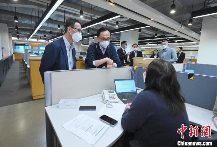 聶德權(quán)(左二)與在電話熱線中心協(xié)助市民登記“疫苗到戶接種服務(wù)”的明愛(ài)專上學(xué)院學(xué)生交談?！∠愀厶貐^(qū)政府新聞處供圖