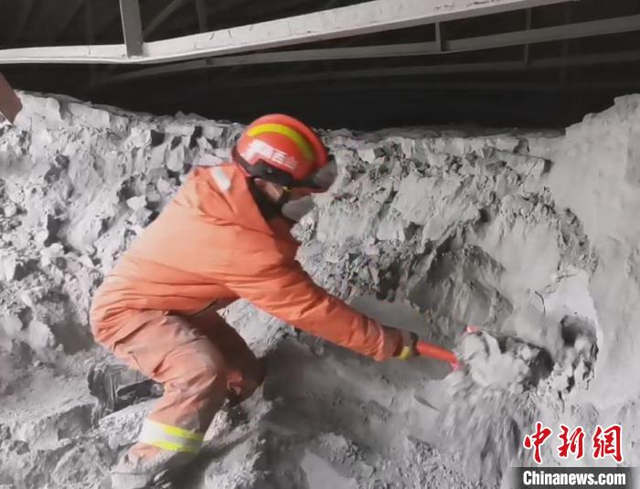 一名消防員單腿跪在粉煤灰堆上搜救被困人員。　齊帥 攝