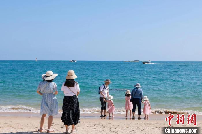 資料圖：家長帶著孩子在海邊嬉浪?！∮谓ㄐ?攝