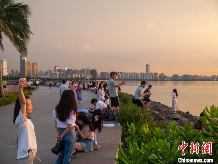 在海邊拍攝夕陽(yáng)美景的游客?！×栝?攝