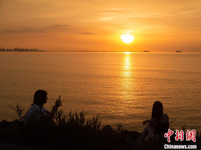 游客在海邊與夕陽(yáng)美景合影?！×栝?攝