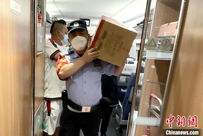 乘警扛著餅干等食物到車(chē)廂分發(fā)給旅客。　徐州鐵路公安處供圖