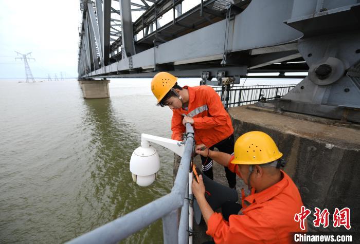 6月24日，南鐵九江橋工段的橋梁工正在九景衢鐵路鄱陽(yáng)湖大橋上對(duì)監(jiān)控?cái)z像頭進(jìn)行檢修?！『鷩?guó)林 攝
