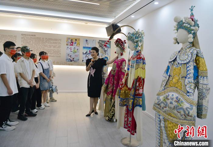 圖為福建省實驗閩劇院工作人員為研學(xué)體驗營學(xué)生介紹閩劇戲服。　張斌 攝
