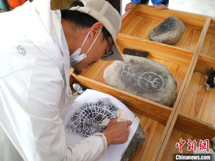 臺青用墨包為巖畫印記上色?！±钤?攝