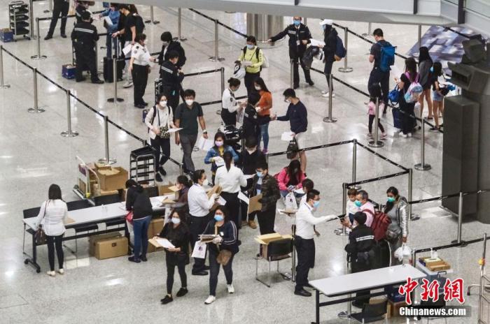圖為香港特區(qū)政府人員在機場禁區(qū)為從各地到港人士戴上手帶作強制檢疫監(jiān)察之用。<a target='_blank' href='/'>中新社</a>記者 秦樓月 攝