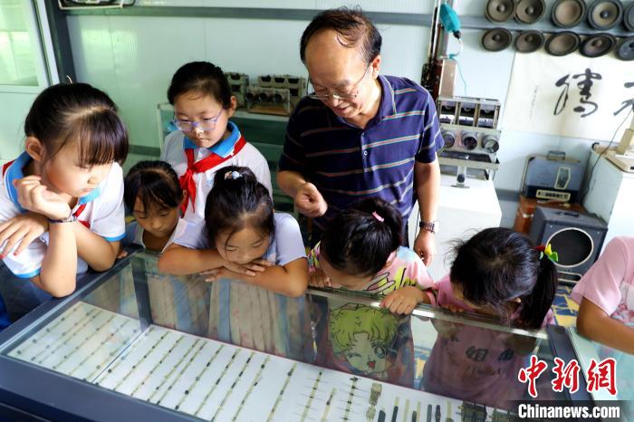 圖為肖光合正在給孩子們介紹收音機(jī)上的零件和電路原理?！∩筹w 攝