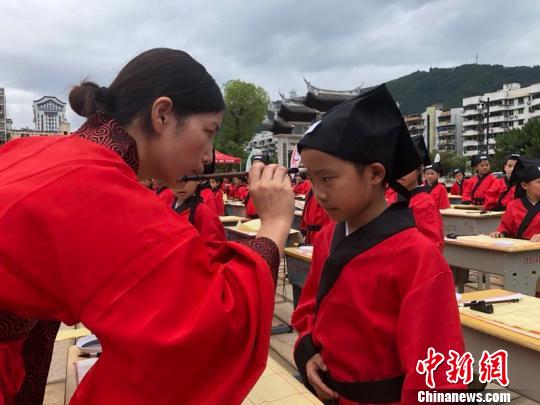 資料圖：在“點朱啟智”環(huán)節(jié)，先生在學童的額心點上朱砂，寓意孩子從此開啟智慧，目明心亮。曉東 攝
