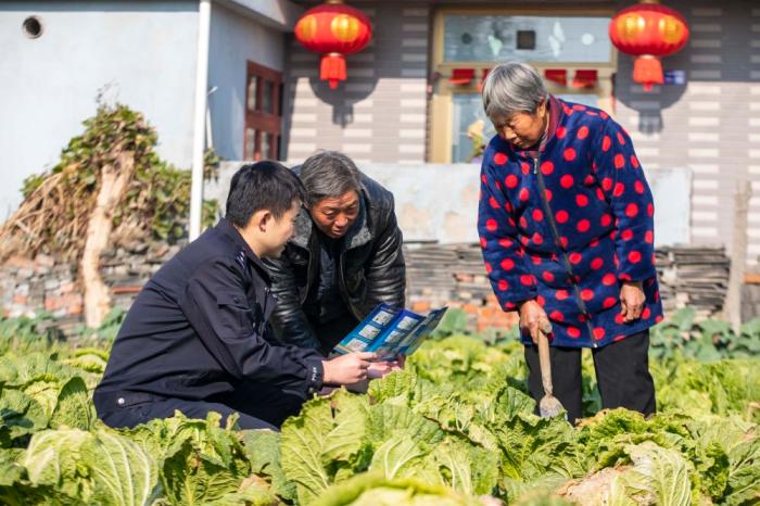 　江蘇省泰州市海陵區(qū)蘇陳派出所民警在蘇陳社區(qū)田間地頭向農(nóng)戶進(jìn)行普法宣傳(2021年12月4日攝)。新華社發(fā)(湯德宏 攝)