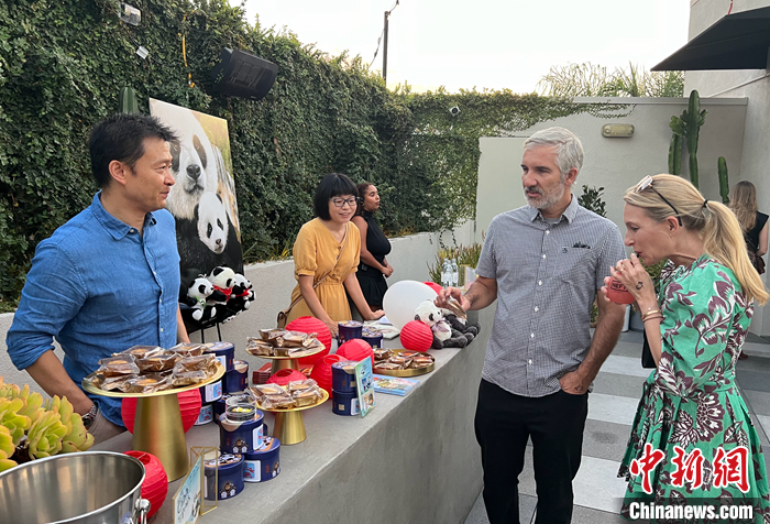 圖為中國駐洛杉磯旅游辦事處主任吳大偉（左一）向美國來賓介紹傳統(tǒng)的中秋佳節(jié)，邀請他們品嘗月餅。 <a target='_blank' href='/'>中新社</a>記者 張朔 攝