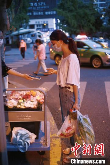 手提兩袋蔬菜的成都市民在選購(gòu)鮮花?！∈茉L者供圖