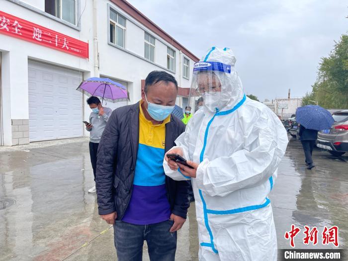 圖為王衛(wèi)玲(右)幫助做核酸的人員進行個人信息登記?！≈煊例?攝