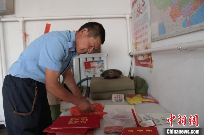 圖為謝建民整理當(dāng)兵時(shí)的榮譽(yù)證書?！『鷸|育 攝