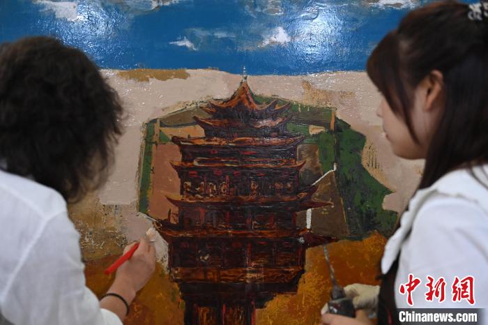 圖為劉志剛與學(xué)生進(jìn)行敦煌元素漆畫創(chuàng)作?！±顏嘄?攝