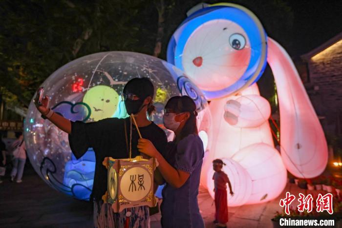 年輕人在燈市擺放著的“兔子燈”前留影?！°蟛?攝