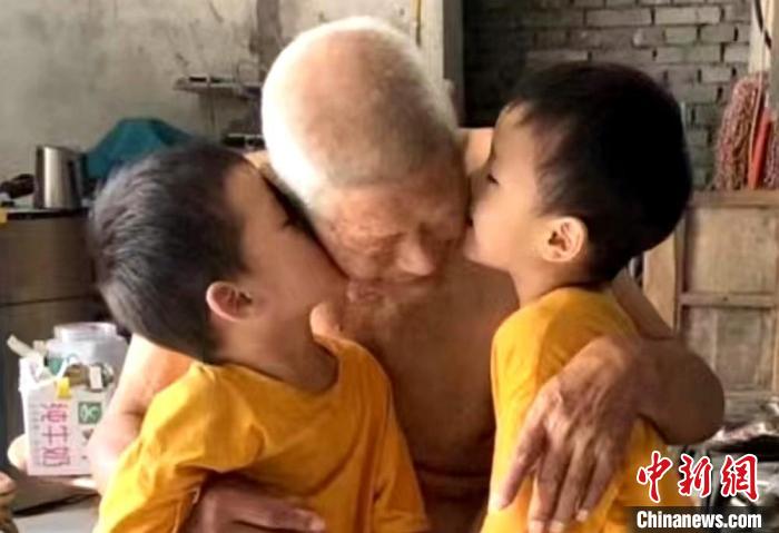 雙胞胎重孫依偎在太爺爺懷里，親吻太爺爺。　劉笑供圖