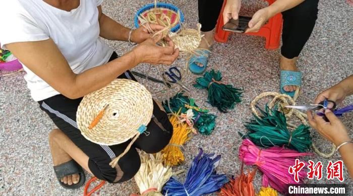 眾人正在用彩色玉米皮編織工藝品?！⒖÷?　攝
