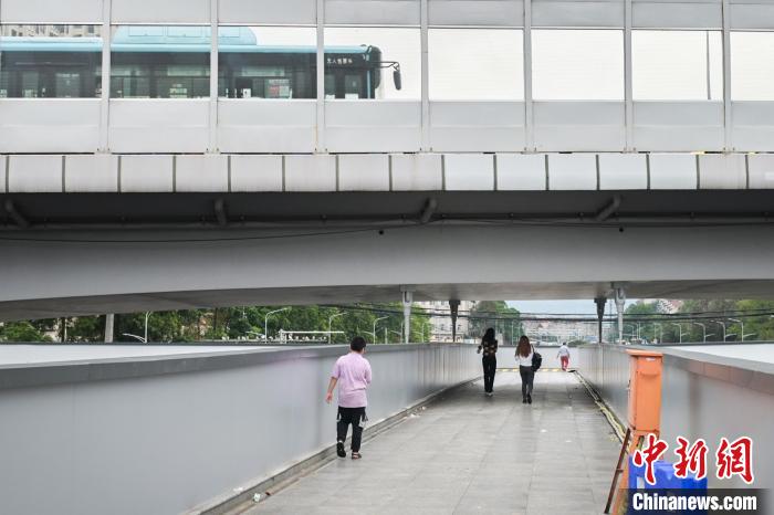 圖為市民走在天橋上，公交車從頭頂?shù)缆否傔^?！∨硇拟?攝