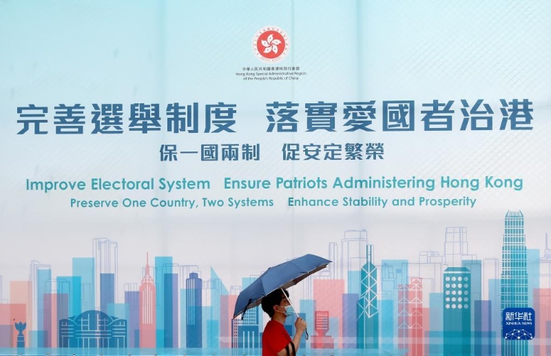 一名香港市民從“完善選舉制度 落實(shí)愛國者治港”巨幅海報(bào)前經(jīng)過(2021年3月31日攝)。新華社記者 吳曉初 攝