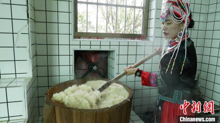 圖為藍(lán)春花鏟出煮熟的糯米進(jìn)行釀酒?！∮浾呷A山 攝