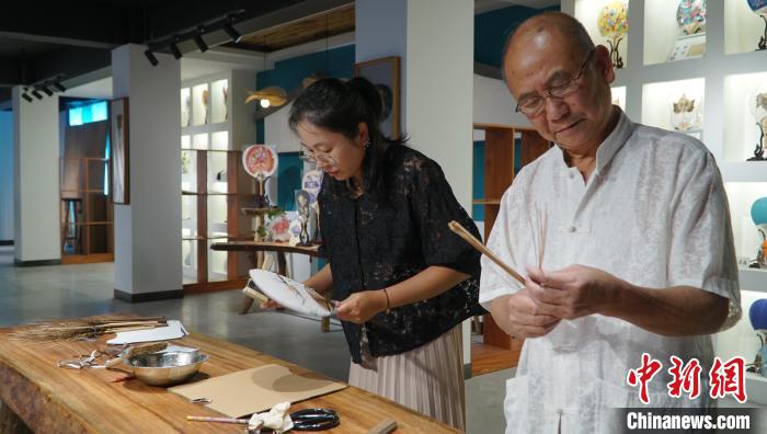 黃碩夫(右)和女兒黃可人(左)一起制作團扇。　李嬌陽 攝