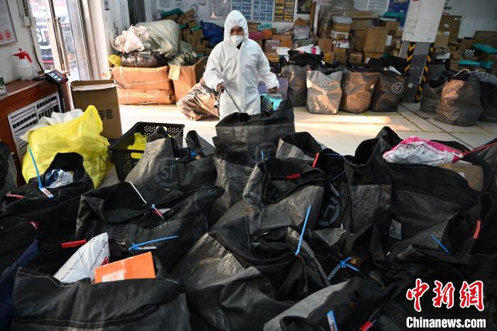圖為工作人員正在對快遞包裹進(jìn)行消殺?！⑽娜A 攝