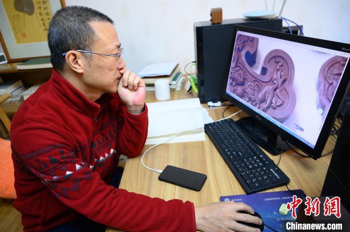 孫晟坐在電腦前，瀏覽設計成品圖片?！№f亮 攝