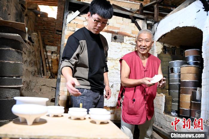 在窯口，林俊徒弟把已上釉的素坯傳給師傅?！埥鸫?攝