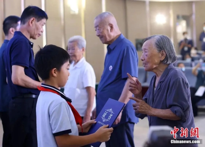 圖片南京大屠殺幸存者夏淑琴(右一)、葛道榮(右二)、艾義英(右三)向南京大屠殺幸存者后代代表頒發(fā)“南京大屠殺歷史記憶傳承人”證書。泱波 攝