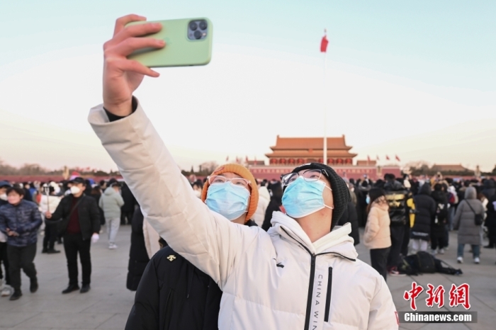 2023年1月1日晨，北京天安門廣場(chǎng)舉行隆重的升國(guó)旗儀式。人們來到天安門廣場(chǎng)觀看升旗儀式，迎接新年。圖為市民拍照留念。 <a target='_blank' href='/'>中新社</a>記者 趙文宇 攝