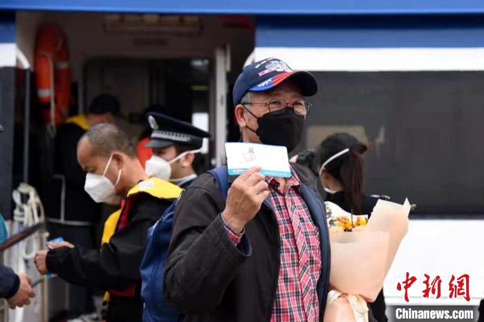 搭乘泉金航線的乘客展示手中的船票?！∪?攝