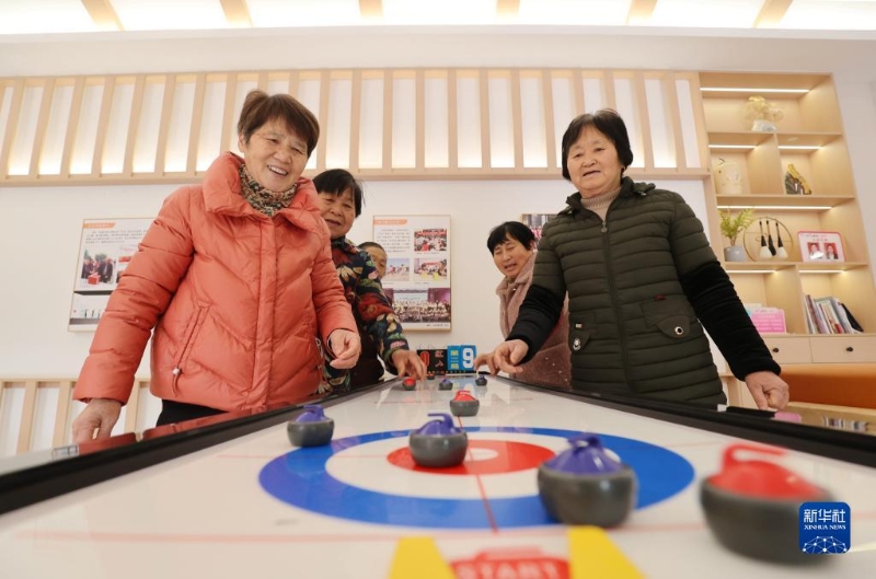 2月16日，在湖州市德清縣阜溪街道興山未來(lái)社區(qū)居家養(yǎng)老服務(wù)中心，社區(qū)老人在打“桌上冰壺球”。（圖源：新華社）