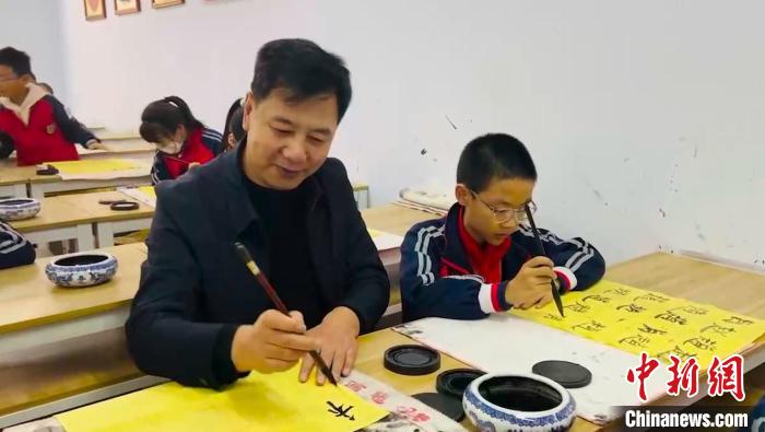 圖為“校長爺爺”同學(xué)生們一起練書法?！￡惙?攝