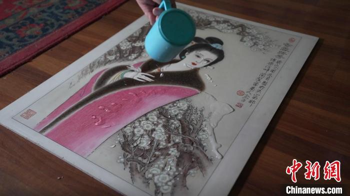 藺烈演示在板刻線畫作品上做防水試驗，展示作品不僅防水還不掉色，濕水后還可用布擦拭?！∪诸?攝