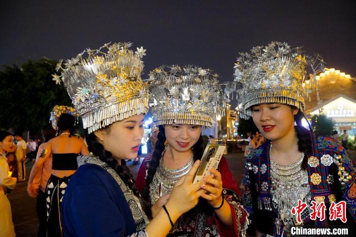 圖為身著苗族服飾的游客正在翻看照片?！№f國政 攝