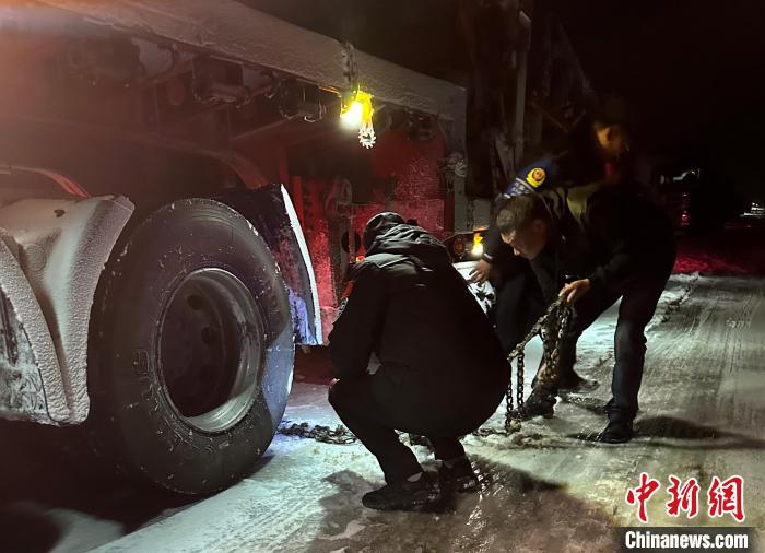 圖為民警幫助受困車輛安裝防滑鏈。　果洛州委宣傳部供圖