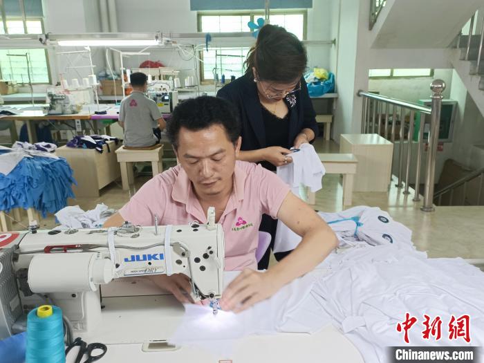 圖為李王花查看服裝制作細節(jié)?！堅潞?攝