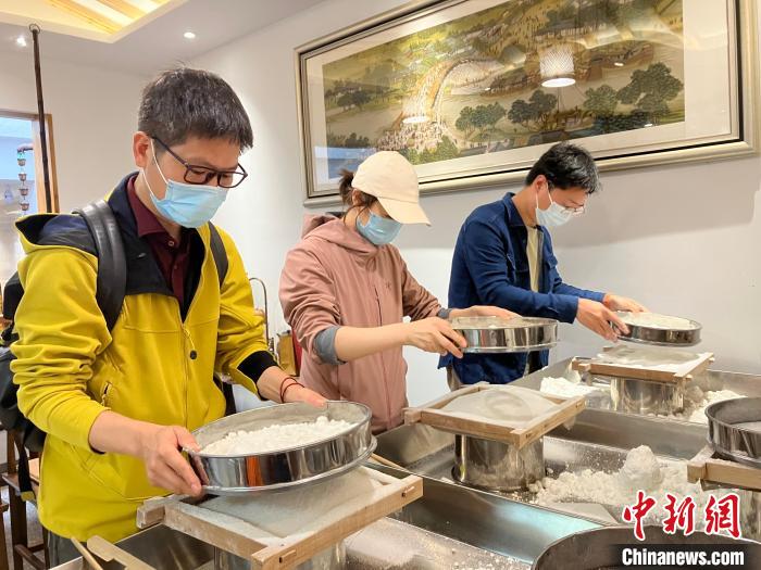 記者篩粉，嘗試制作梁弄大糕 胡豐盛 攝