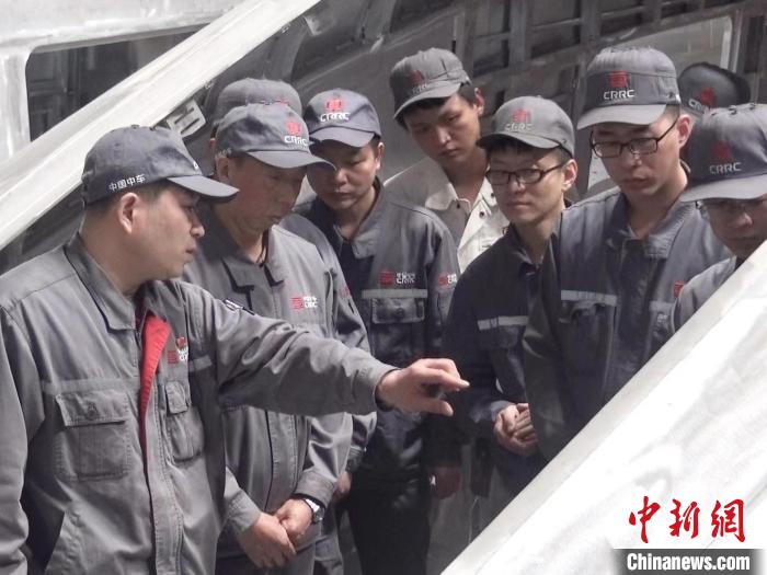 周晶輝正在為徒弟們講解司機室前窗框平度控制?！∈茉L者供圖