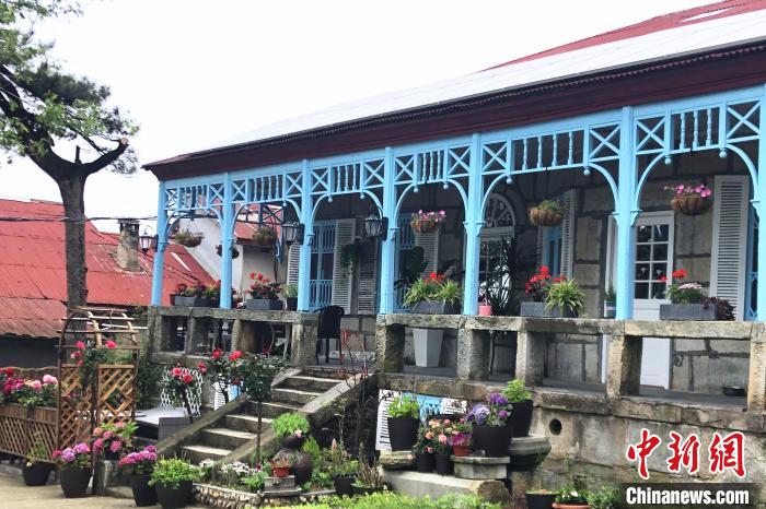 走進(jìn)喬尼·約翰遜在廬山上租住的別墅，藍(lán)色敞開式外廊，一排石條凳上平均間隔的木頭柱支撐著拱券?！蛆i泉 攝