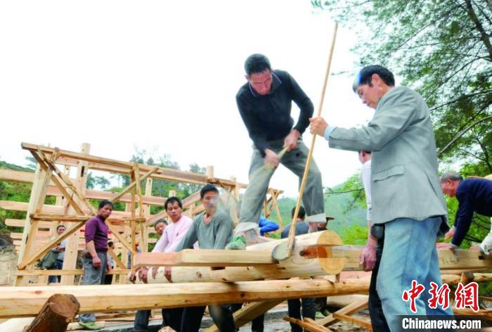 資料圖為木拱廊橋建造過程中，匠人們正在“搭屋架”?！↓徑?攝