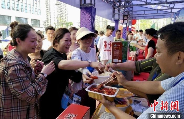 圖為江西南昌英雄城啤酒龍蝦燒烤節(jié)上，游客爭相品嘗鐵河小龍蝦預(yù)制菜?！⌒陆▍^(qū)融媒體中心供圖