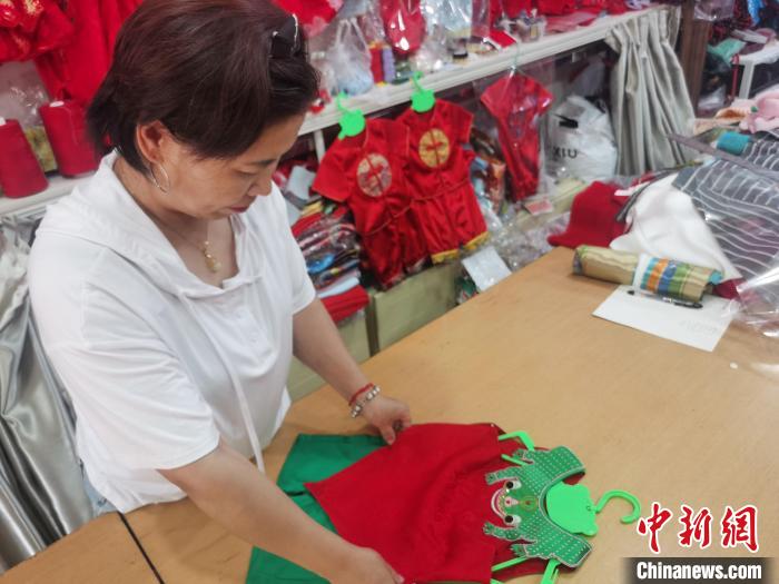 圖為勝芳古鎮(zhèn)一家兒童傳統(tǒng)服飾店，店員正在整理剛做好的青蛙衫。　邢亞南 攝